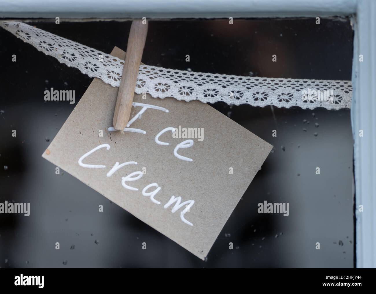 Affiche de crème glacée accrossée à la dentelle dans la fenêtre du magasin annonçant les desserts de glace aux clients du café à emporter Banque D'Images