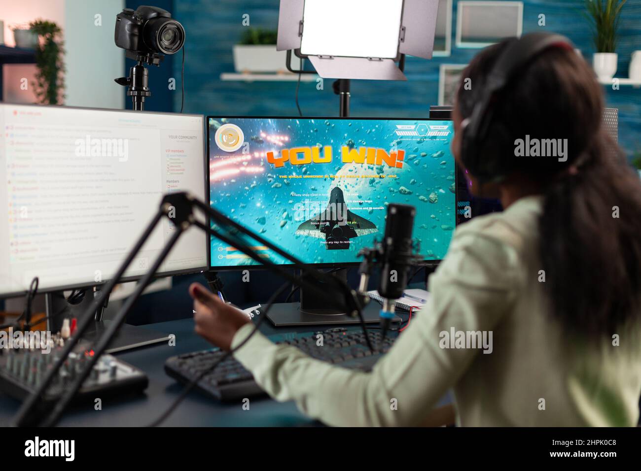 Une joueuse gagnant jeu de tir de l'espace jeu de jeux vidéo en discutant avec des joueurs utilisant le microphone pendant la diffusion en direct, gagnant réussi jouant des jeux vidéo en ligne avec ordinateur RGB Banque D'Images