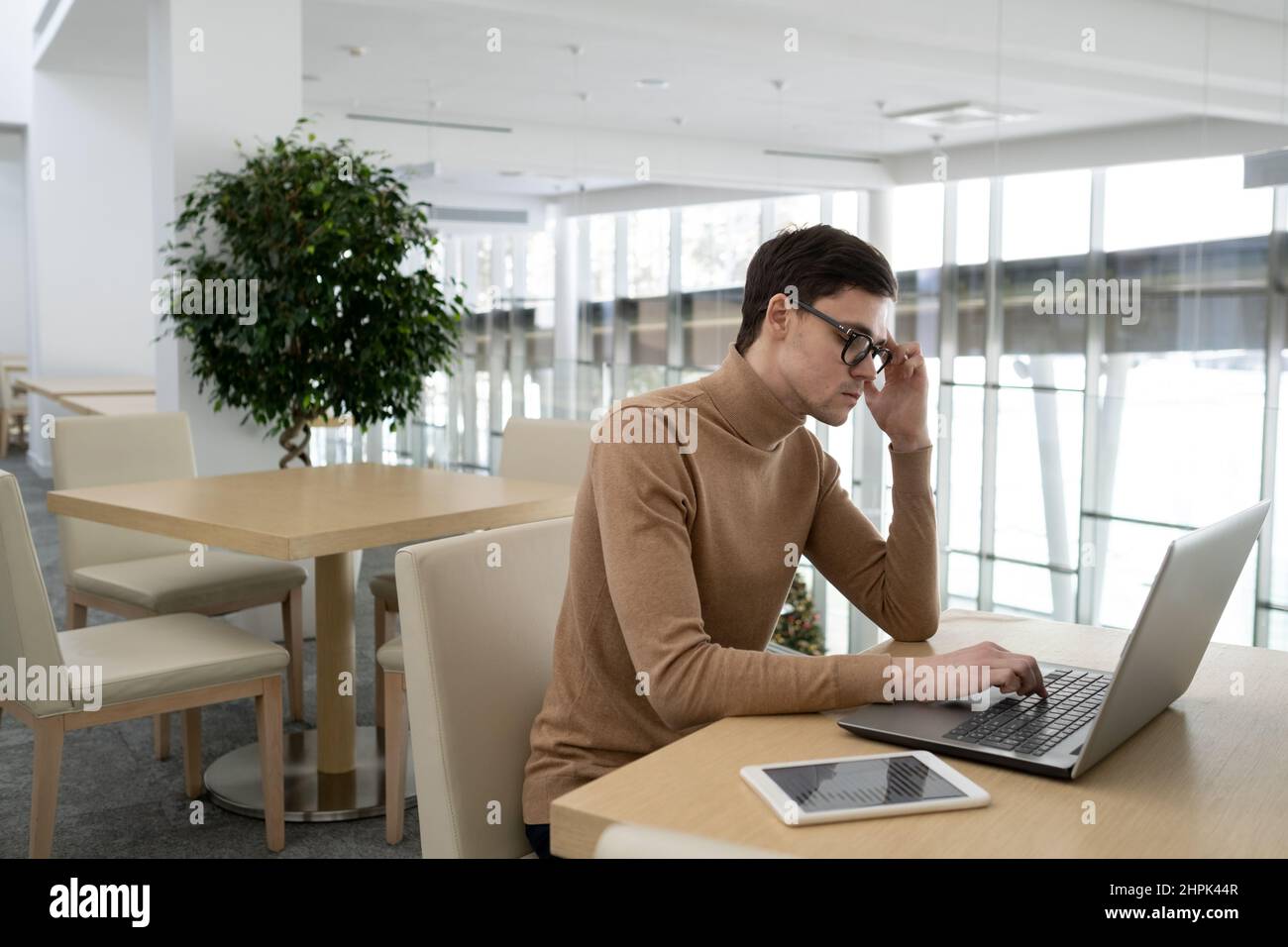 Jeune homme d'affaires se concentrant sur le travail sur le nouveau projet tout en étant assis devant un ordinateur portable par bureau dans le bureau de la société de technologie moderne Banque D'Images