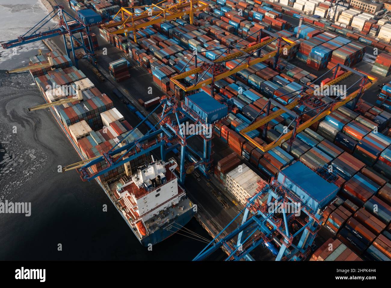 Vladivostok, Russie - 26 janvier 2022 : Vue de dessus du terminal des conteneurs du port maritime.En hiver, un bateau à conteneurs est en train de charger à l'embarcadère. Banque D'Images