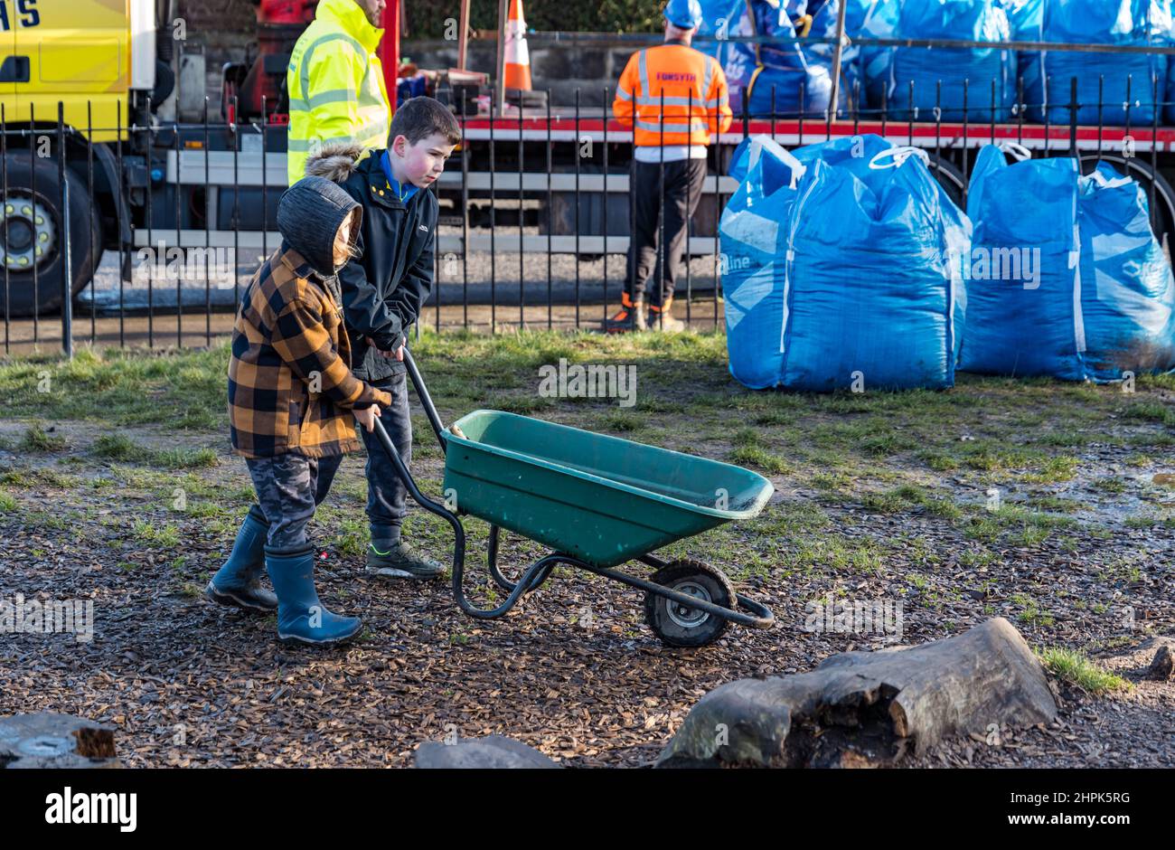 Trinity Primary School, Édimbourg, Écosse, Royaume-Uni, 22 février 2022. Terre végétale pour les écoles : excavation pendant le projet de biomes du jardin botanique royal, un surplus de terre végétale de 50 tonnes est accordé aux écoles, aux allotissements et aux organismes communautaires par la société de construction Balfour Beatty. Une livraison de 5 tonnes a lieu à l'école primaire Trinity pour transporter la terre ou la terre pour remplir les planteurs dans le jardin de l'école pour que les élèves cultivent des légumes. Les élèves du primaire 4 utilisent des récipients de toutes formes et tailles pour déplacer la terre pour remplir les planteurs ; un travail d'équipe est nécessaire Banque D'Images