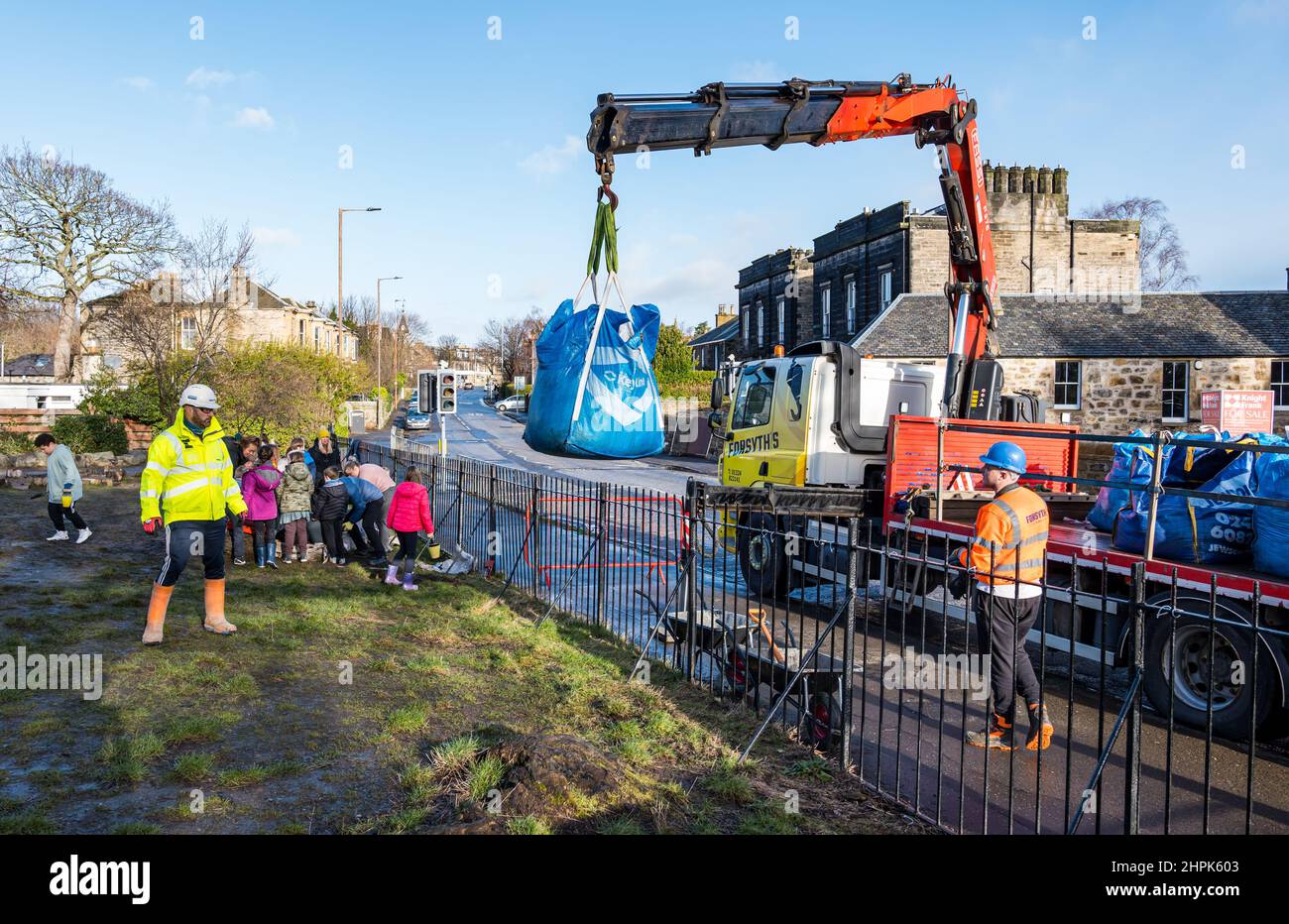 Trinity Primary School, Édimbourg, Écosse, Royaume-Uni, 22 février 2022. Terre végétale pour les écoles : excavation pendant le projet de biomes du jardin botanique royal, un surplus de terre végétale de 50 tonnes est accordé aux écoles, aux allotissements et aux organismes communautaires par la société de construction Balfour Beatty. Une livraison de 5 tonnes a lieu à l'école primaire Trinity pour transporter la terre ou la terre pour remplir les planteurs dans le jardin de l'école pour que les élèves cultivent des légumes. Les élèves du primaire 4 utilisent des récipients de toutes formes et tailles pour déplacer la terre pour remplir les planteurs ; un travail d'équipe est nécessaire Banque D'Images
