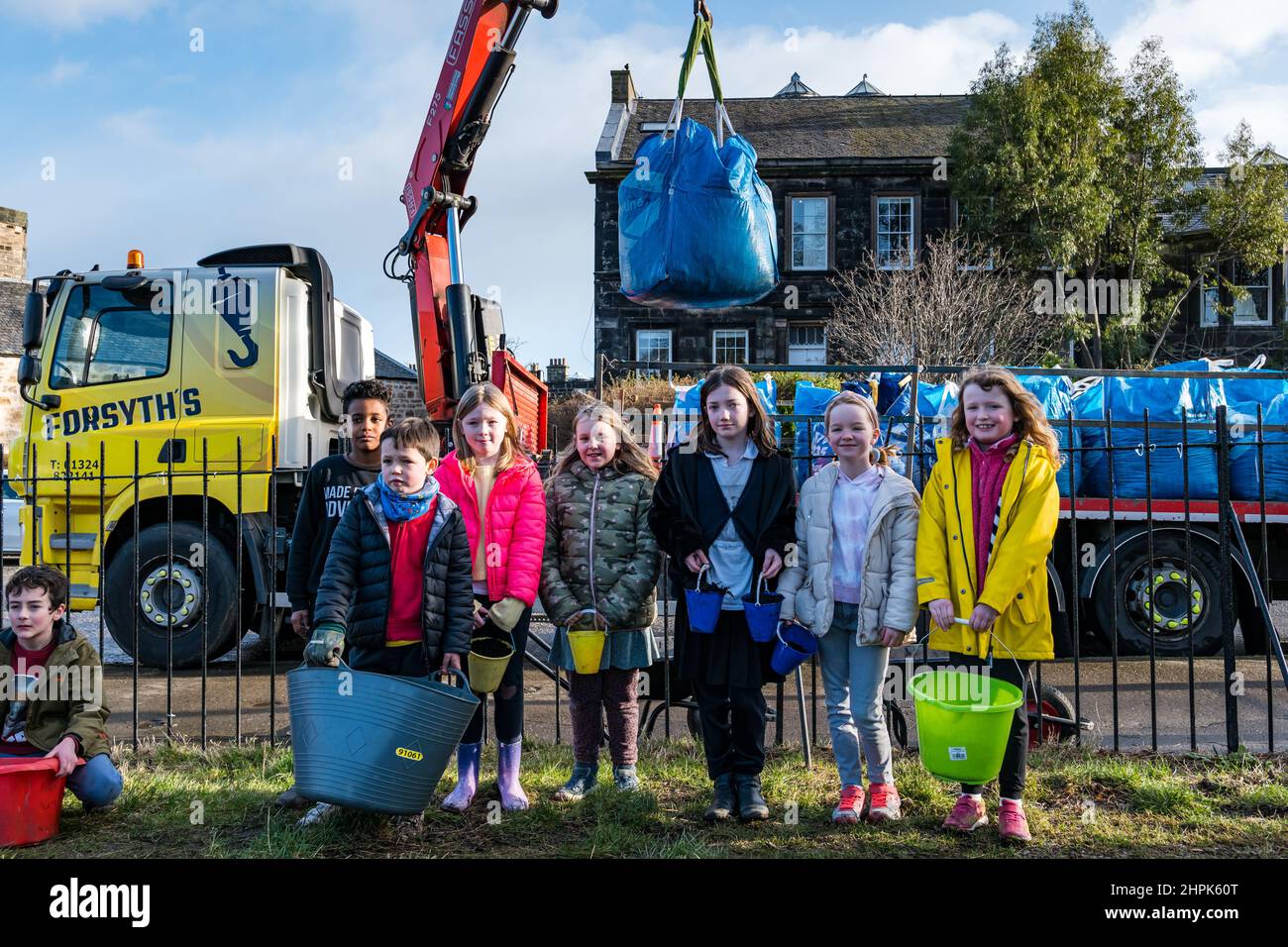 Trinity Primary School, Édimbourg, Écosse, Royaume-Uni, 22 février 2022. Terre végétale pour les écoles : excavation pendant le projet de biomes du jardin botanique royal, un surplus de terre végétale de 50 tonnes est accordé aux écoles, aux allotissements et aux organismes communautaires par la société de construction Balfour Beatty. Une livraison de 5 tonnes a lieu à l'école primaire Trinity pour transporter la terre ou la terre pour remplir les planteurs dans le jardin de l'école pour que les élèves cultivent des légumes. Les élèves du primaire 4 utilisent des récipients de toutes formes et tailles pour déplacer la terre pour remplir les planteurs ; un travail d'équipe est nécessaire Banque D'Images