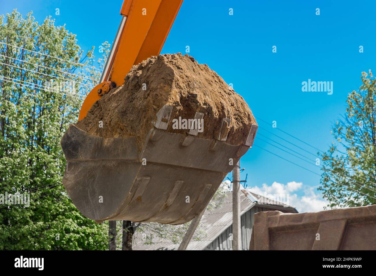 Travaux d'excavation. Godet du tracteur creusant le sol sur un chantier de construction contre le ciel. Banque D'Images