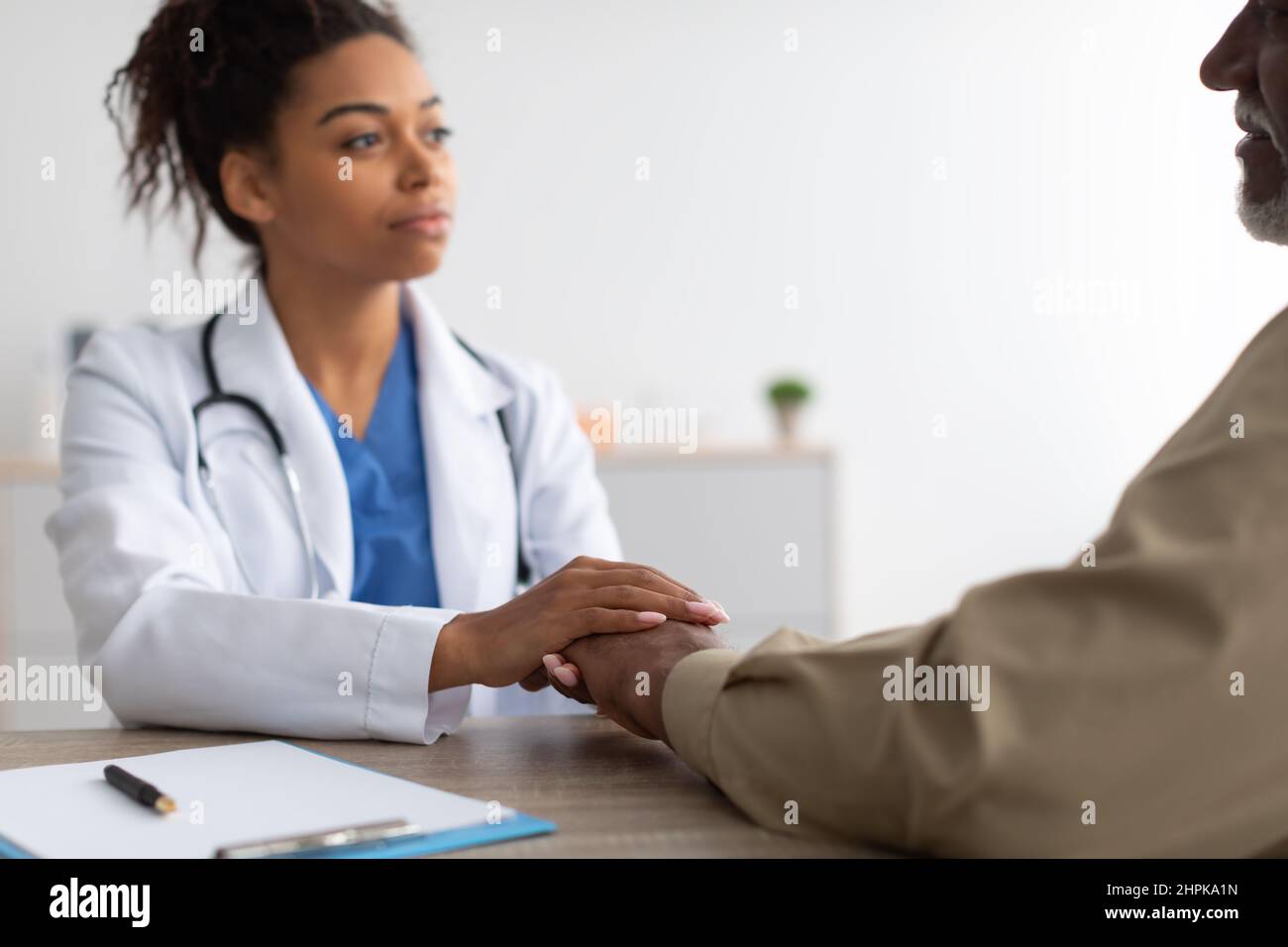 Gros plan d'un médecin de femme noire tenant les mains d'un patient de sexe masculin Banque D'Images