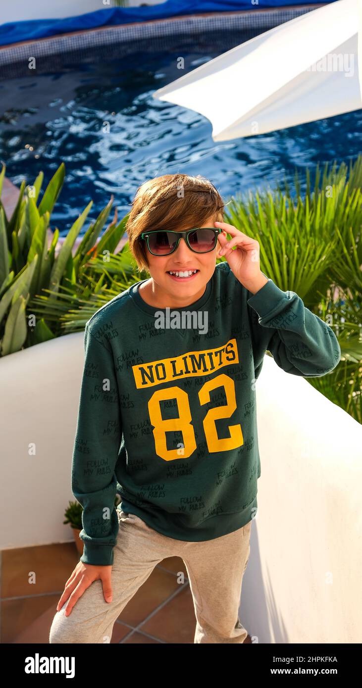 Un adolescent de sport se tient sur les marches au bord de la piscine.  Sweat-shirt vert sport et pantalon gris pour garçon. Sports et mode,  activités de plein air, h Photo Stock - Alamy