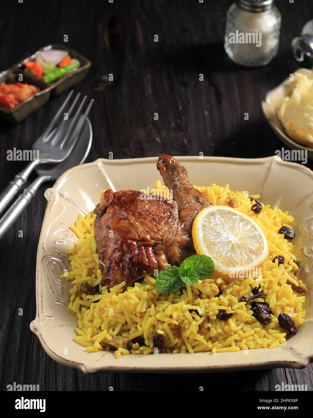 Délicieux poulet épicé Biryani dans une assiette de crème sur fond de bois noir, cuisine indienne ou pakistanaise. Banque D'Images