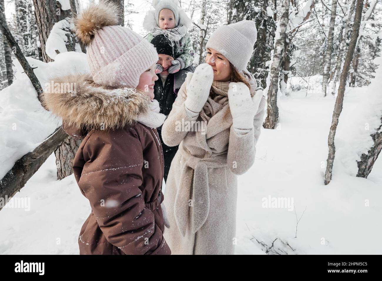 papa avec maman et deux filles s'amuser dans la forêt enneigée Banque D'Images