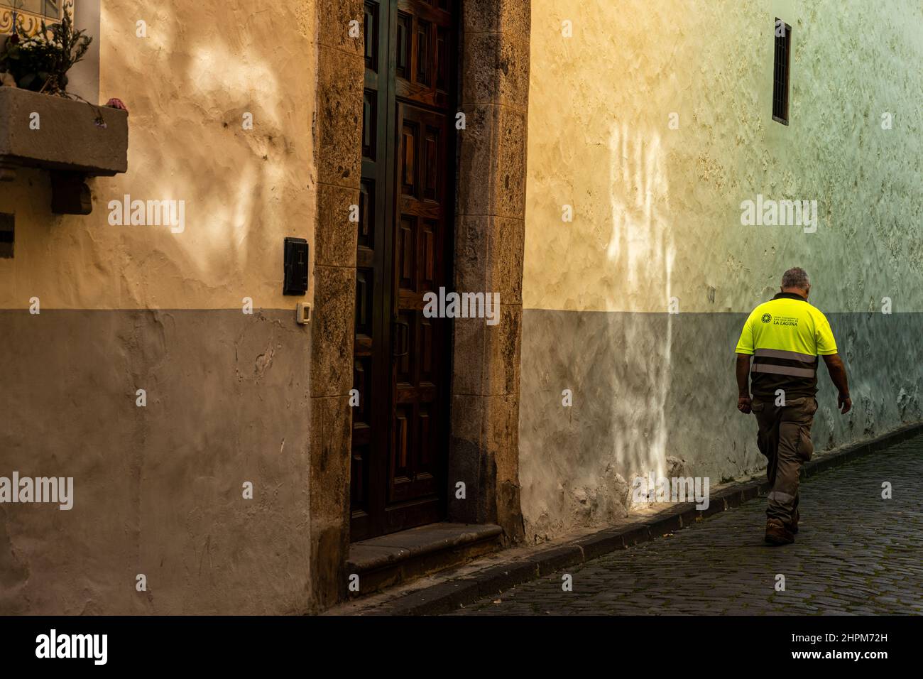 Homme en chemise de haute viz marchant devant un reflet lumineux sur un mur dans le site du patrimoine mondial de San Cristobal de la Laguna, Tenerife, îles Canaries, Espagne Banque D'Images