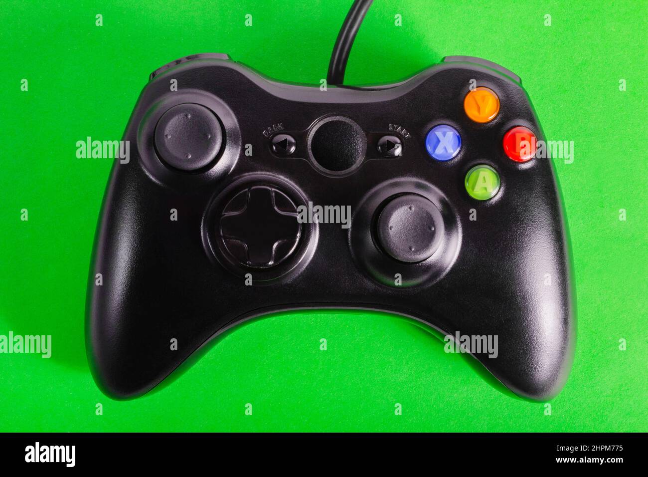 Photo de la manette de jeu moderne et filaire classique sur fond vert. Banque D'Images