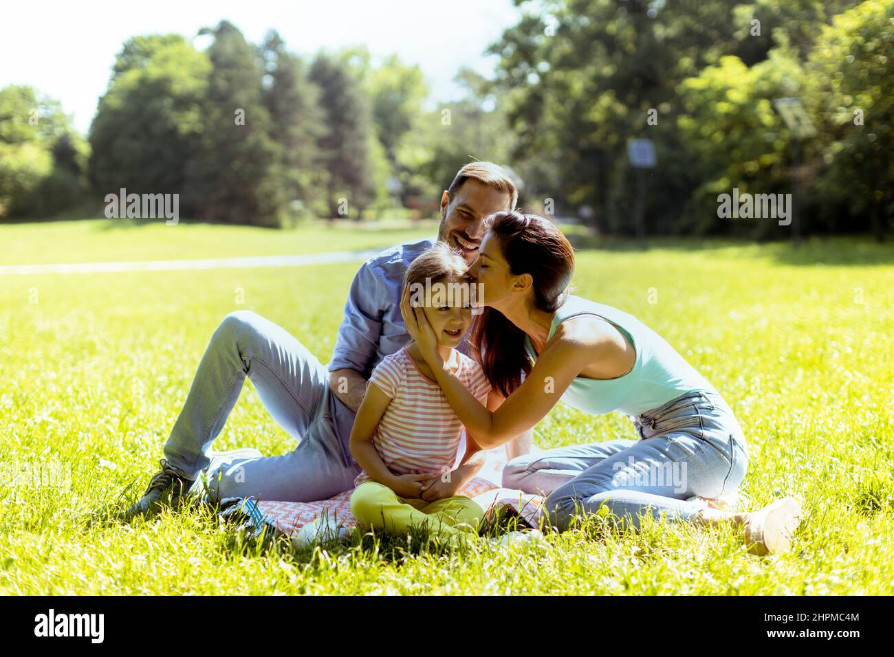 Bonne jeune famille avec petite fille mignonne s'amuser dans le parc par une journée ensoleillée Banque D'Images
