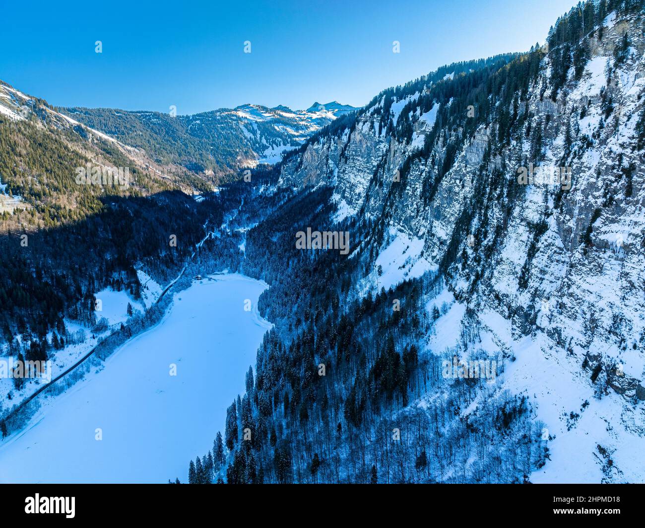 Vue aérienne de l'heure bleue sur le lac gelé entouré par les alpes. Morzine Montriond, France, drone Banque D'Images