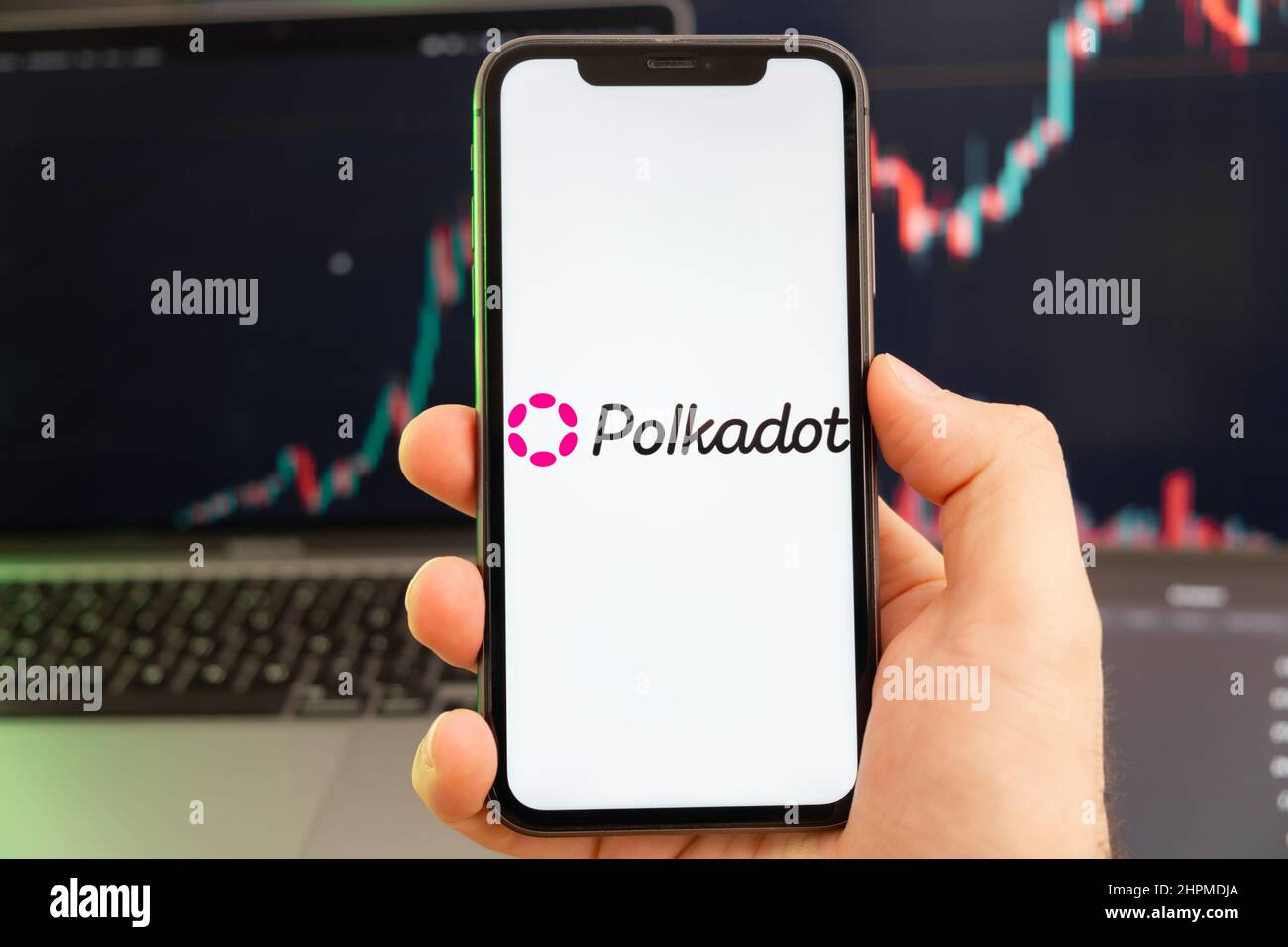 Le logo de la crypto-monnaie Polkadot DOT sur l'écran d'un smartphone dans la main de l'homme avec une tendance croissante sur le tableau sur un fond vert. Banque D'Images