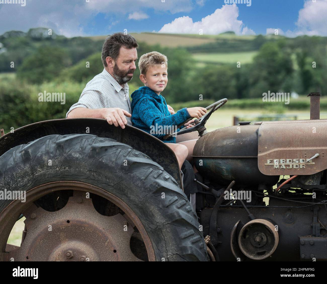 Père enseignant à son fils de conduire un tracteur Banque D'Images