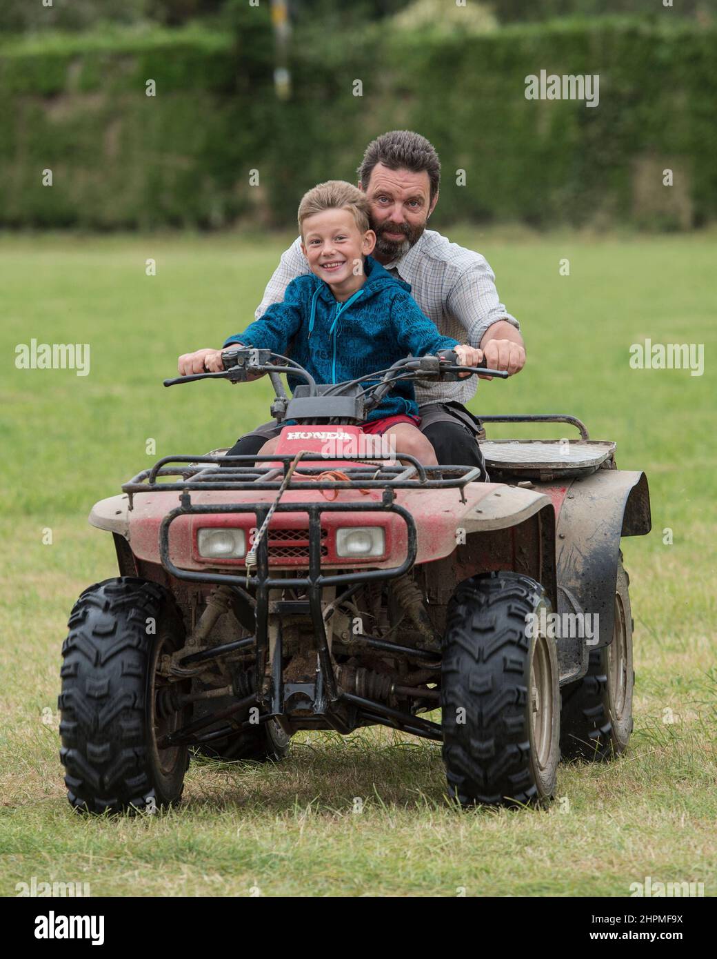 père et fils sur un quadbike sans casque de sécurité Banque D'Images