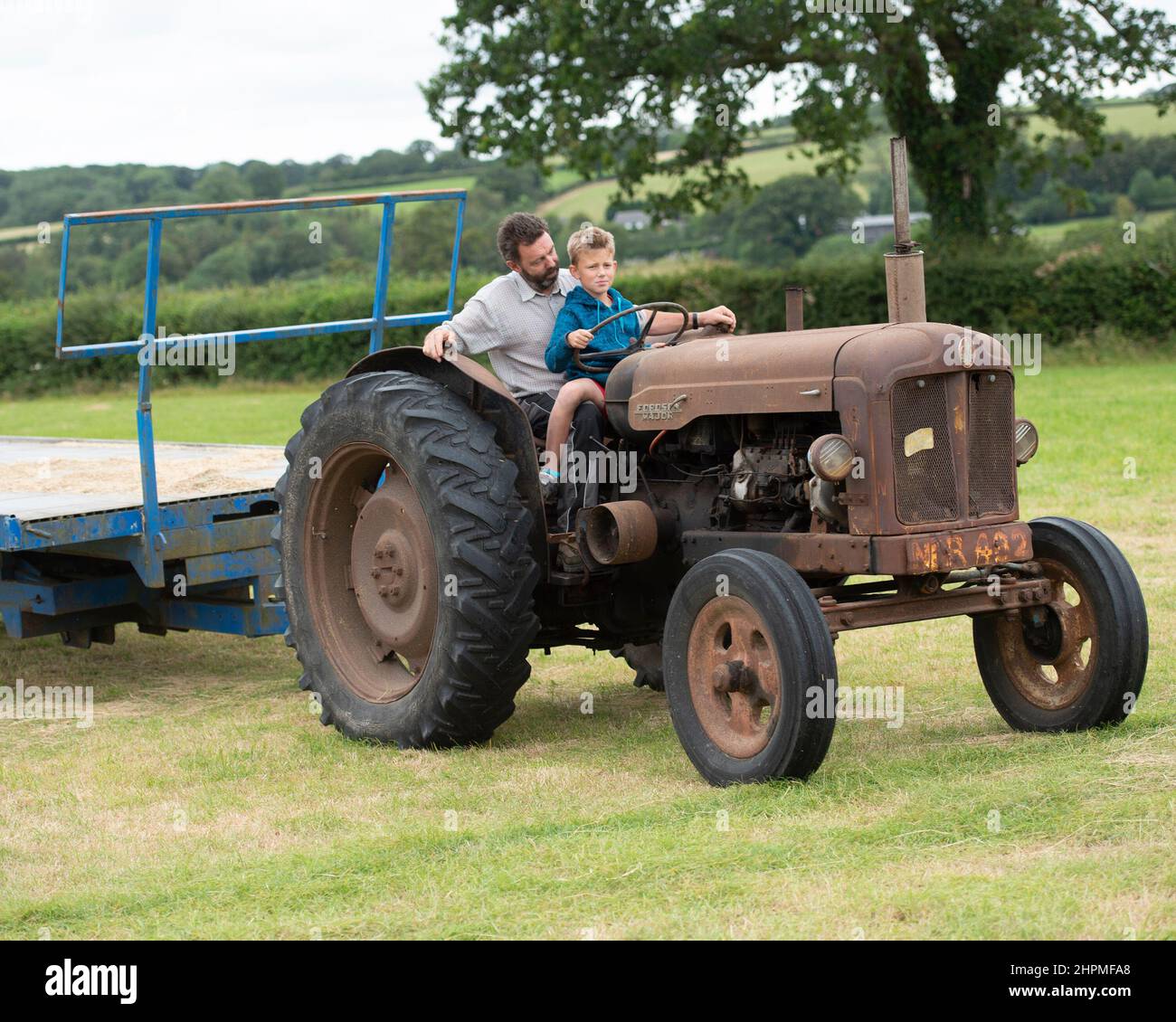 Père enseignant à son fils de conduire un tracteur Banque D'Images