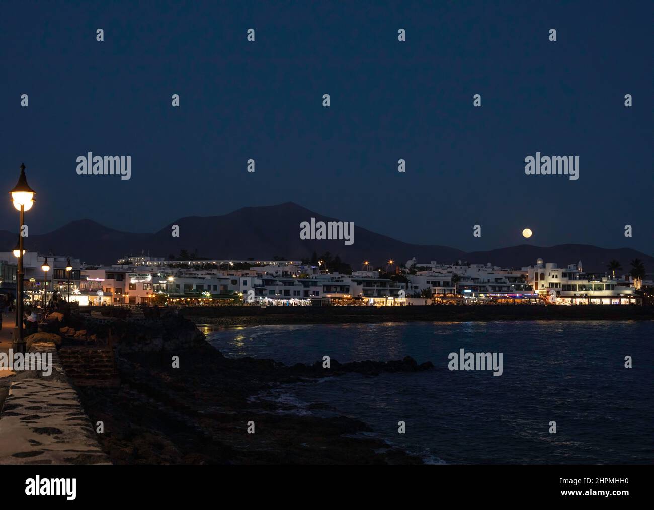 La lune s'élève au-dessus du front de mer de Playa Blanca, Lanzarote, îles Canaries. Espagne. Banque D'Images