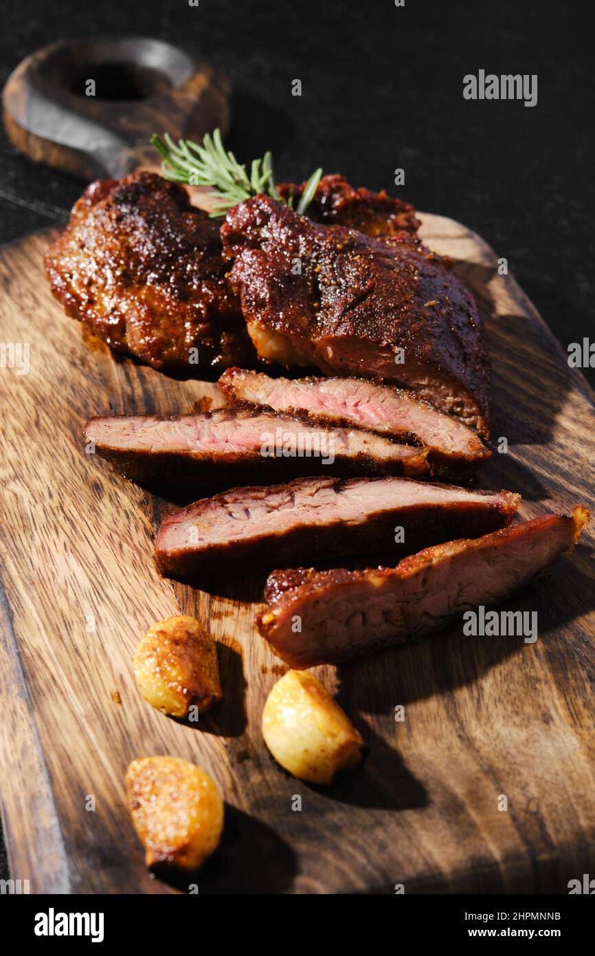 Araignée de beefsteak poêlée dans une poêle en fonte, servie sur une planche à découper en bois avec tomate et basilic Banque D'Images
