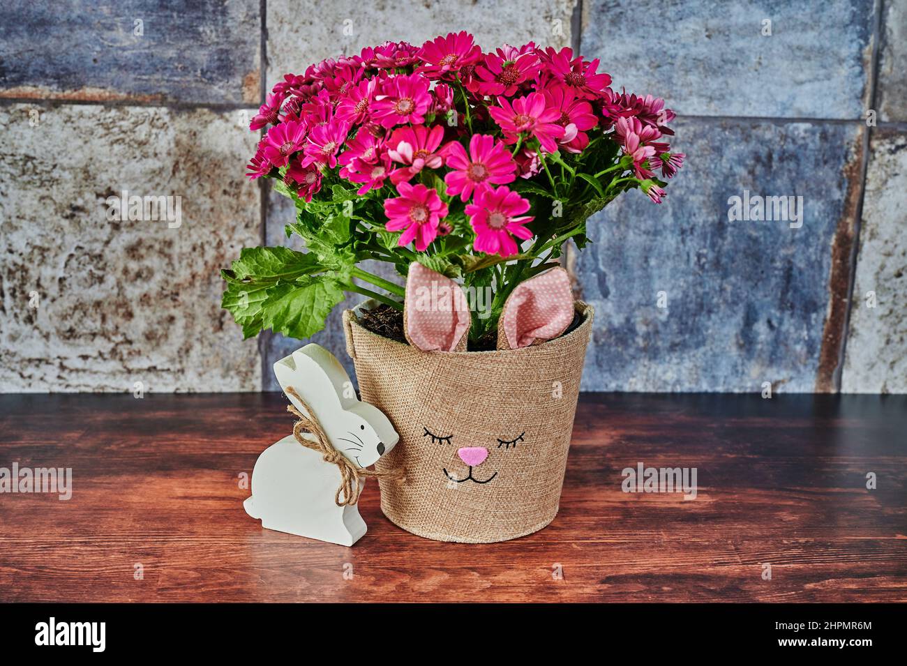 Pot de fleurs avec un visage de lapin et un lapin de Pâques en bois mis au point. Banque D'Images
