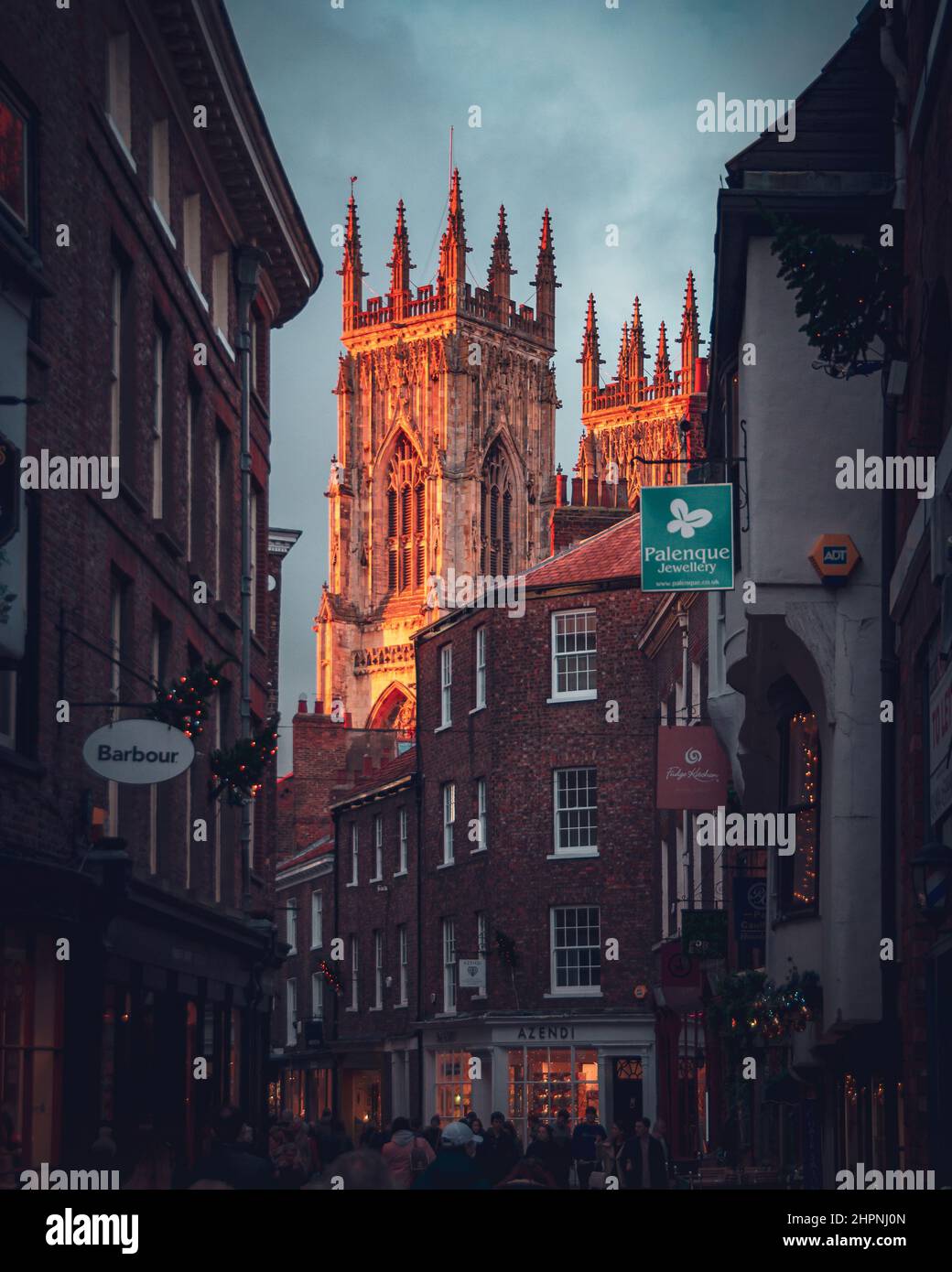 York Minster s'est baigné dans une lumière du soleil chaude en soirée, surplombant les magasins de briques rouges de Low Petrergate Banque D'Images
