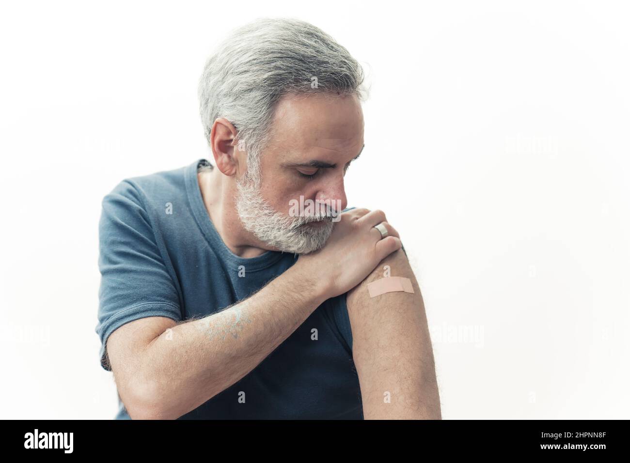 Homme d'âge moyen regardant son bras vacciné - la grippe et la prévention de la propagation du coronavirus. Photo de haute qualité Banque D'Images