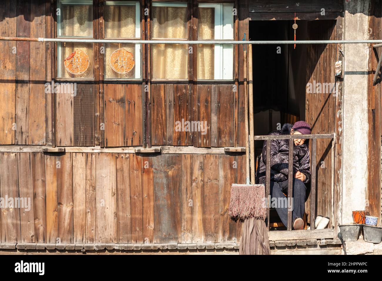 Femme endormi essayant de se réchauffer au soleil d'hiver dans le village aquatique de Wenzhou, en Chine Banque D'Images