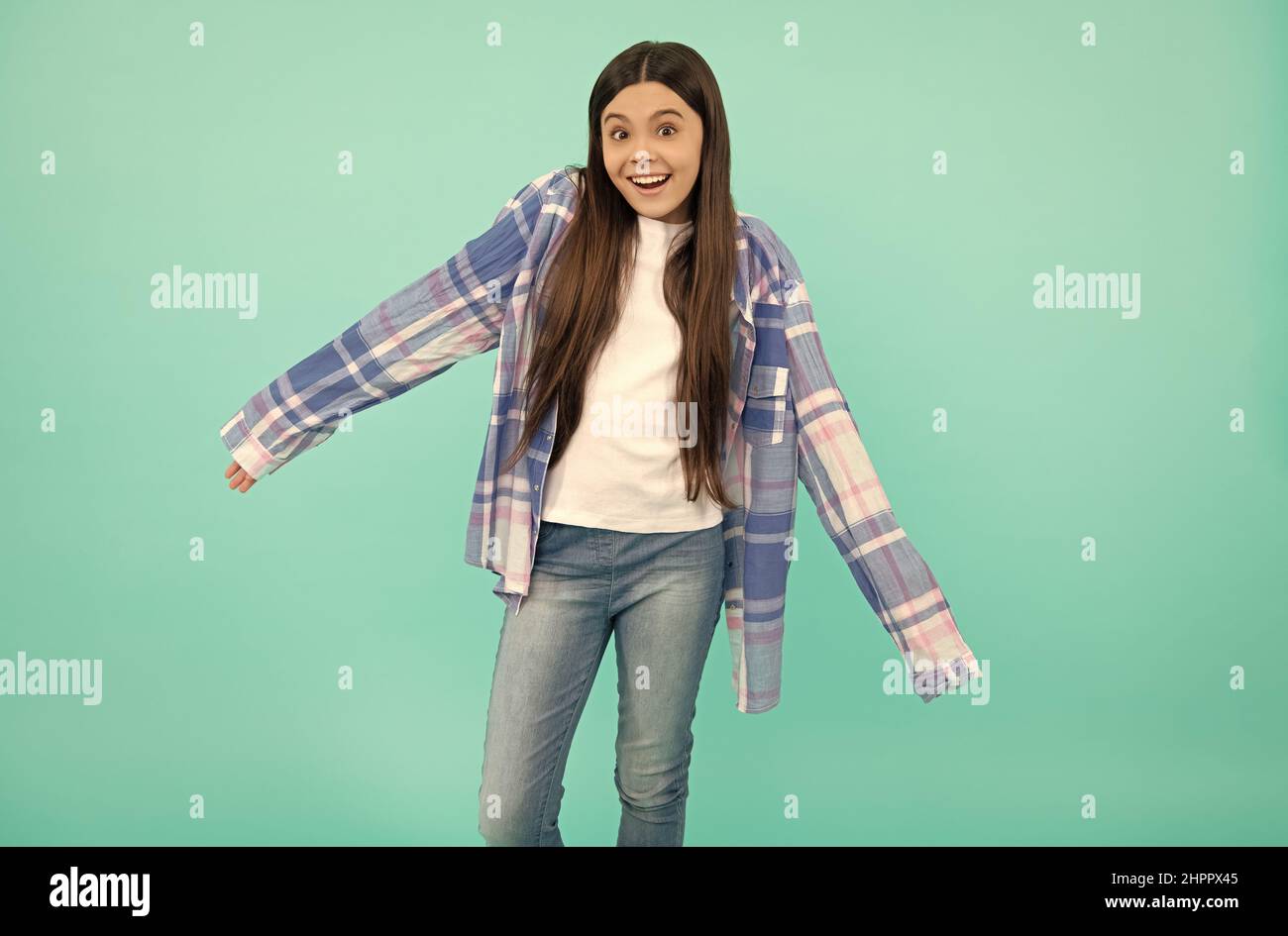 Les manches de chemise sont trop longues.Une adolescente essaie une chemise à carreaux.Mode adolescent Banque D'Images