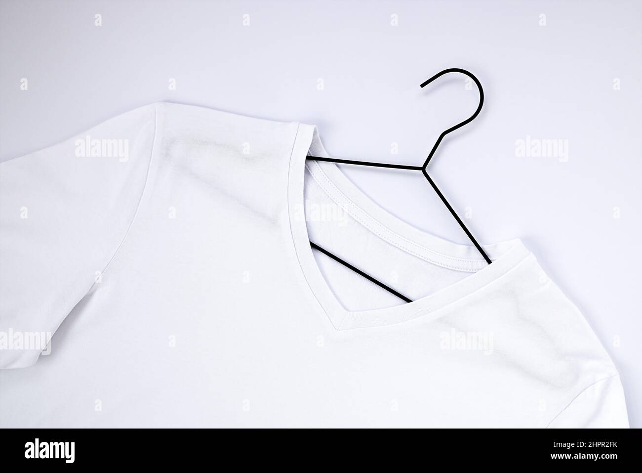 Maquette de t-shirt en coton blanc, sur un cintre noir. Gros plan d'un collier pour une étiquette Banque D'Images