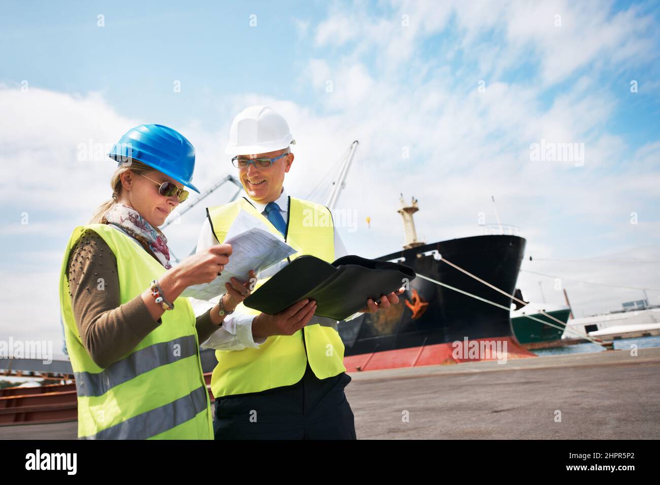 Les efforts combinés créent des résultats. Deux employés de quai qui détiennent des documents pendant qu'ils se trouvent dans le chantier naval. Banque D'Images