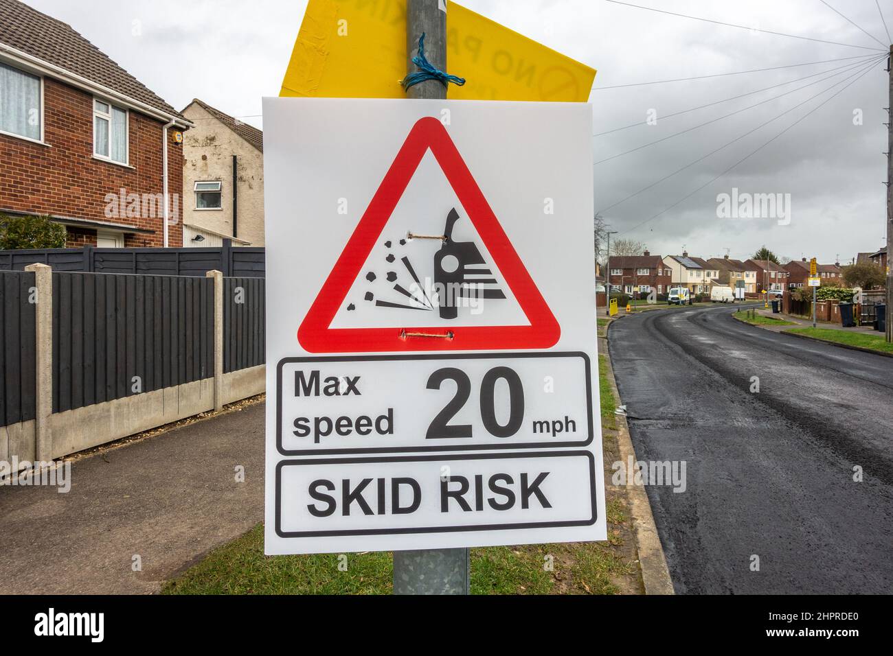 Un panneau de signalisation routière temporaire est fixé à un lampadaire pour signaler un risque de dérapage et préciser une limite de vitesse. Banque D'Images