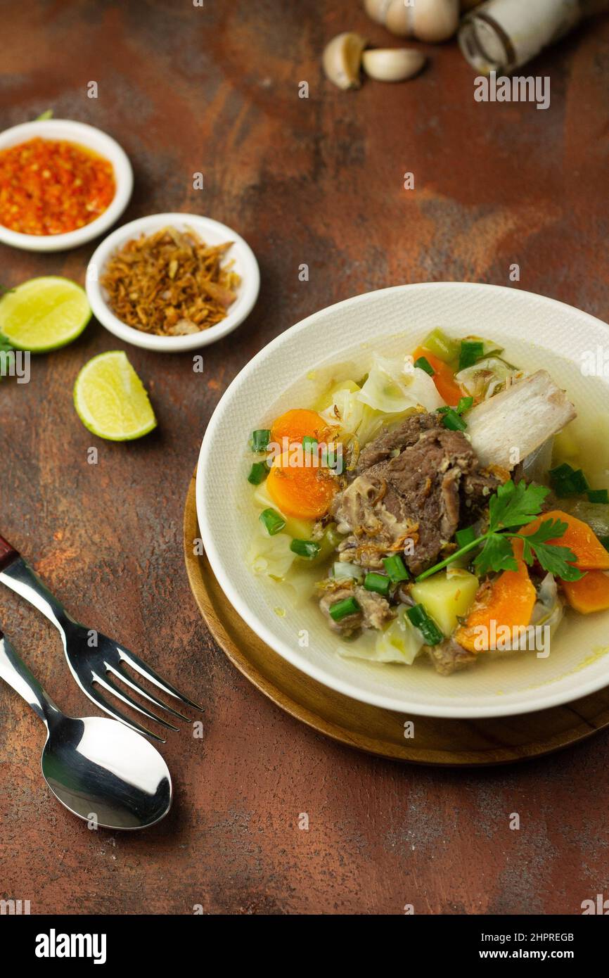 SOP Tulang SAPI ou soupe indonésienne de boeuf clair mélangé avec quelques légumes tels que la carotte, la pomme de terre, le chou et le haricot vert. Servi sur un bol en céramique. Banque D'Images