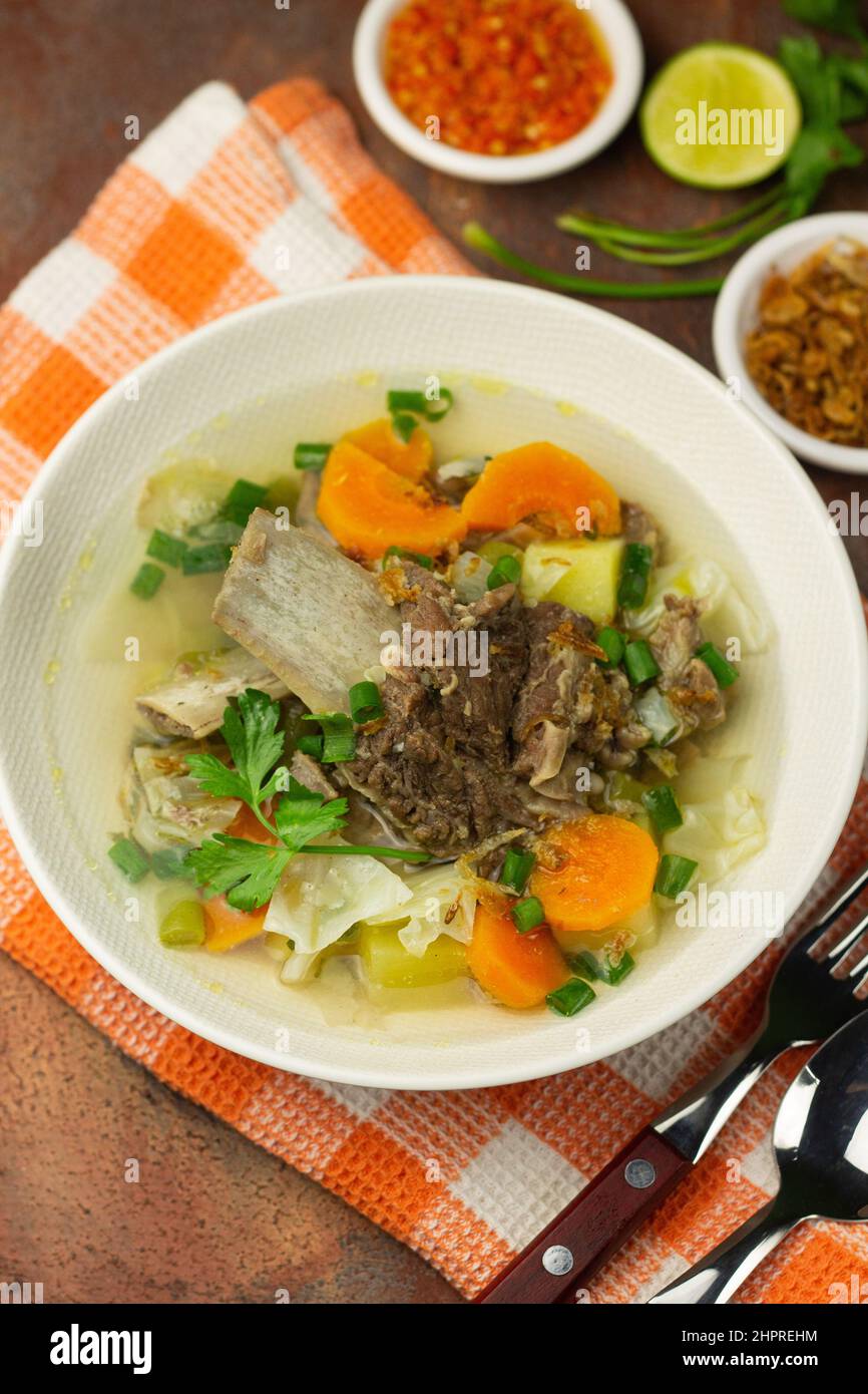 SOP Tulang SAPI ou soupe indonésienne de boeuf clair mélangé avec quelques légumes tels que la carotte, la pomme de terre, le chou et le haricot vert. Servi sur un bol en céramique. Banque D'Images