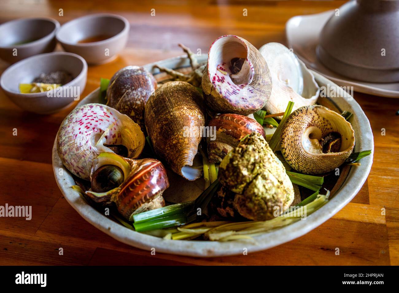 Une assiette remplie de grands escargots dans un restaurant de poissons vivants vietnamiens sur la côte dans le centre du Vietnam. Banque D'Images