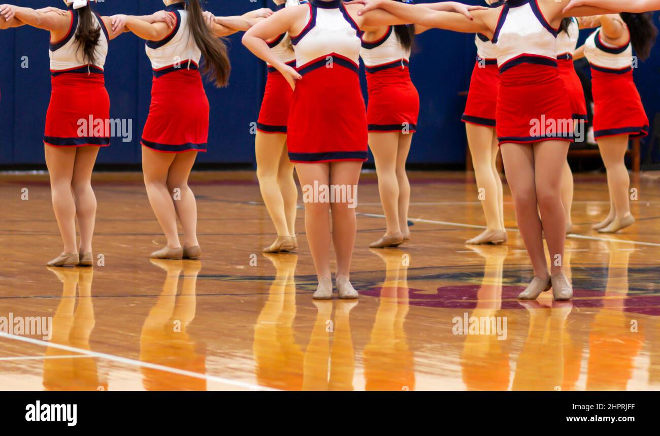 Une équipe de kick line de l'école secondaire se joue dans une salle de gym à la moitié du temps du match de basket-ball. Banque D'Images