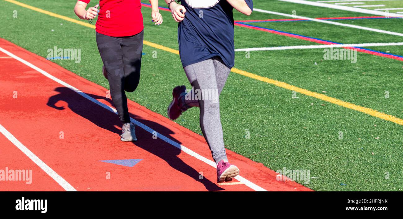Deux filles du lycée qui s'exécutent rapidement sur une piste pendant la piste et l'entraînement sur le terrain. Banque D'Images