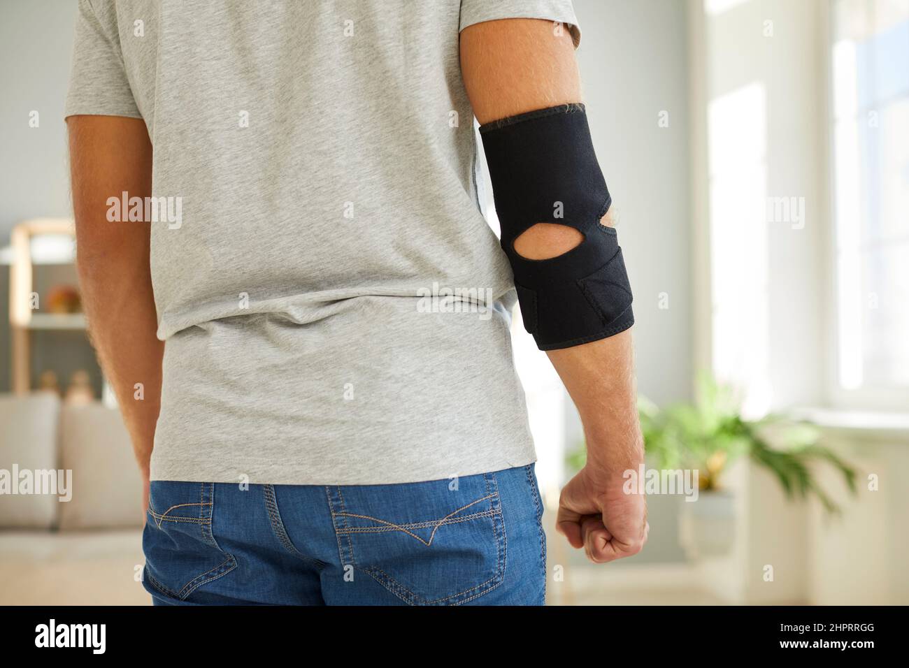 Homme portant un corset orthopédique de soutien de coude pour soulager la douleur dans son coude blessé Banque D'Images