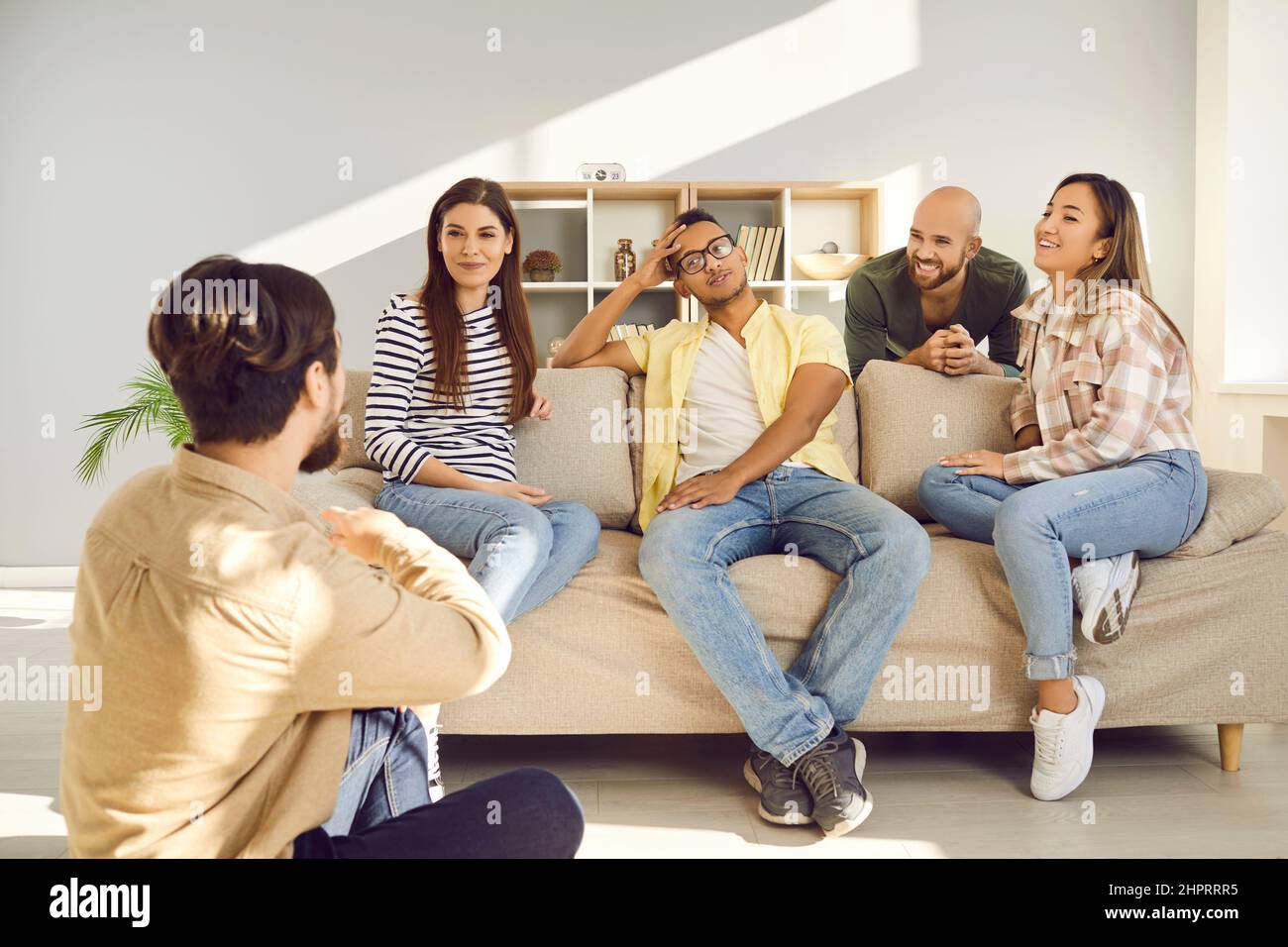De jeunes amis heureux discutant et appréciant le temps ensemble pendant la réunion à la maison le week-end. Banque D'Images