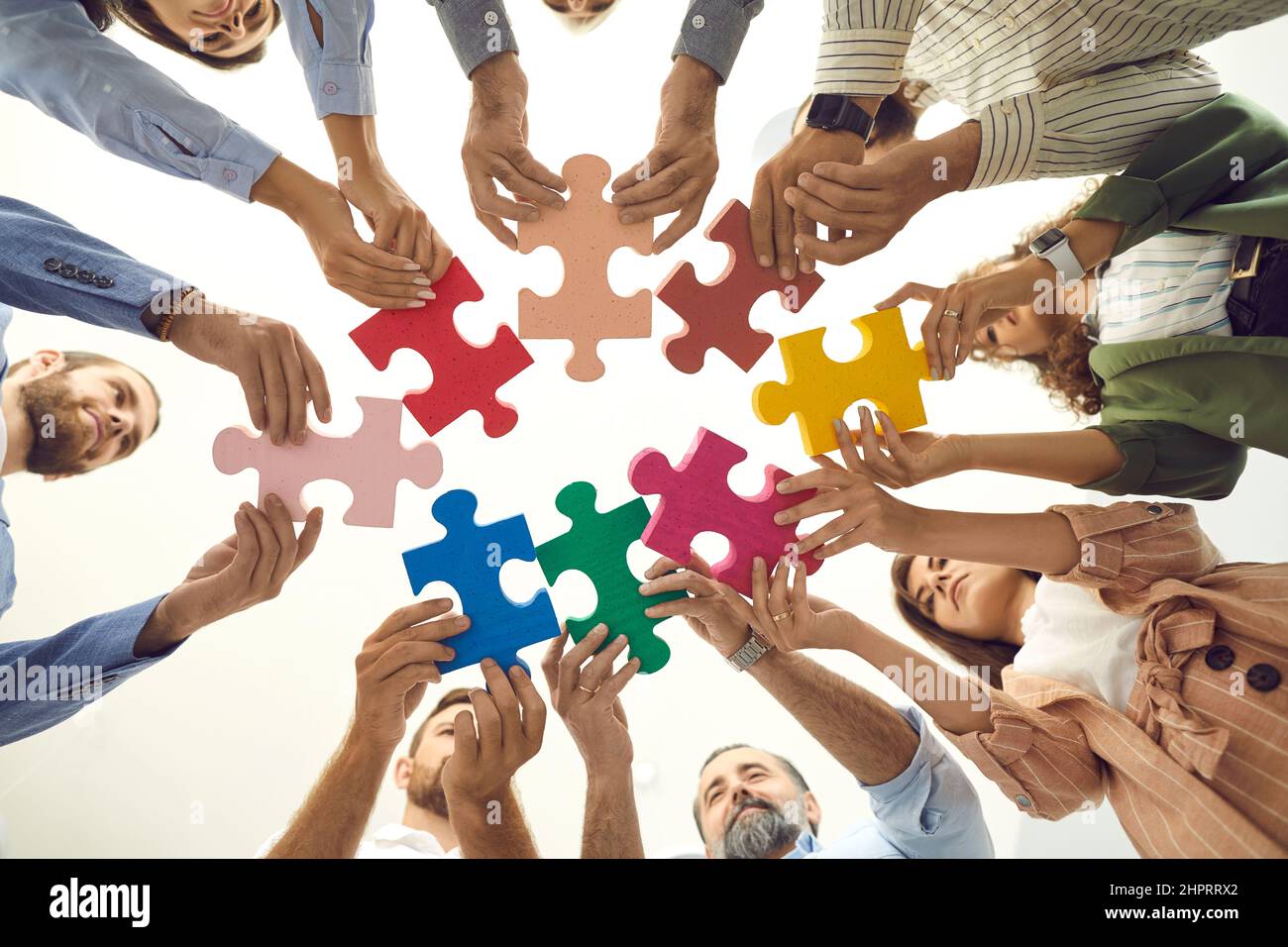 Vue de dessous d'une équipe de professionnels créatifs qui relient des pièces de puzzle Banque D'Images