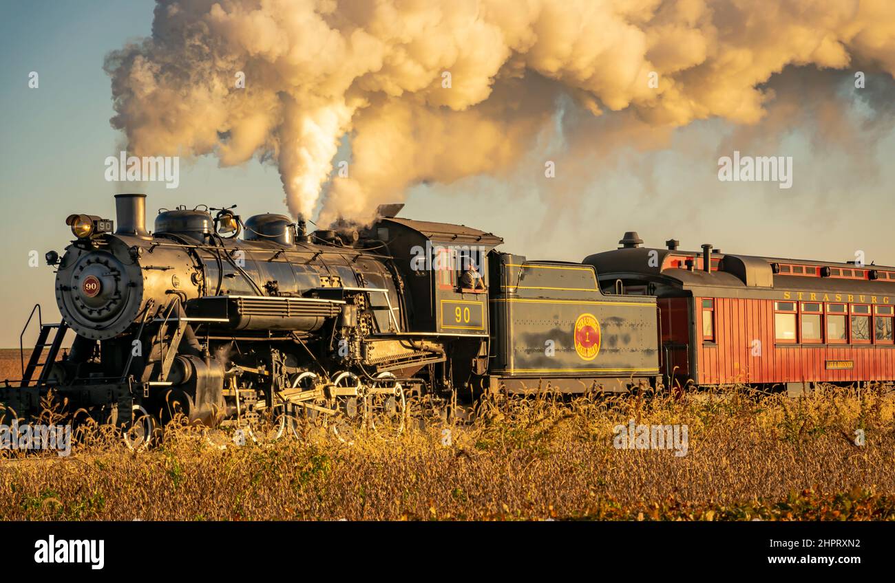 Ronks, Pennsylvanie, octobre 2020 - Une vue d'un train à vapeur passager antique de fumée qui s'approche à travers les arbres ar Sunrise Banque D'Images