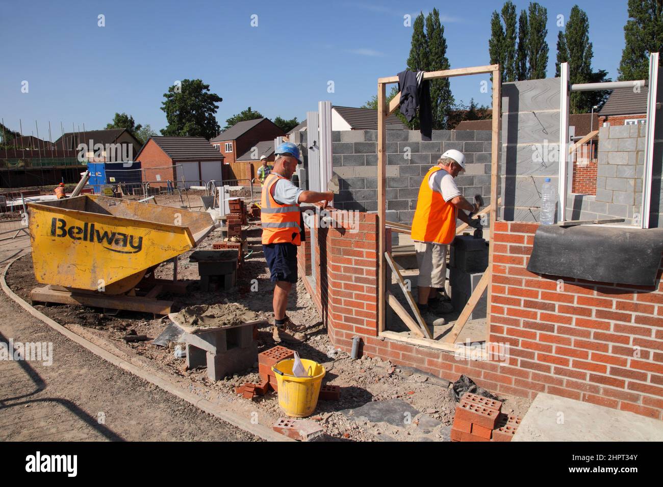 Des constructeurs et des couches de briques travaillent sur un site de construction Bellway Homes dans les West Midlands, en Angleterre, au Royaume-Uni Banque D'Images