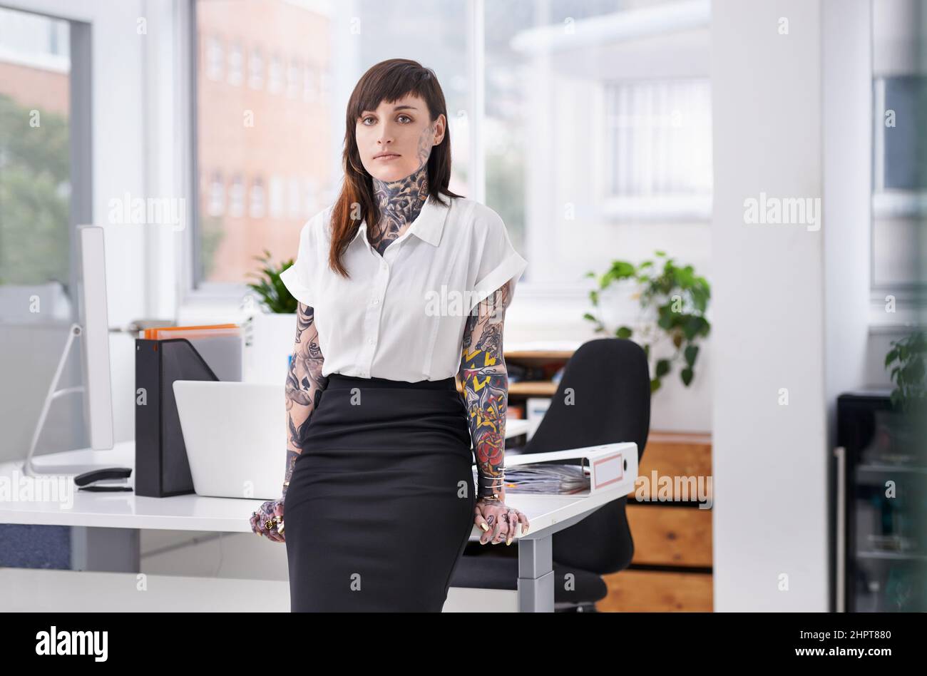 Des shes prêts à faire du rock sur la scène de l'entreprise. Une jeune femme d'affaires couverte de tatouage dans son bureau. Banque D'Images