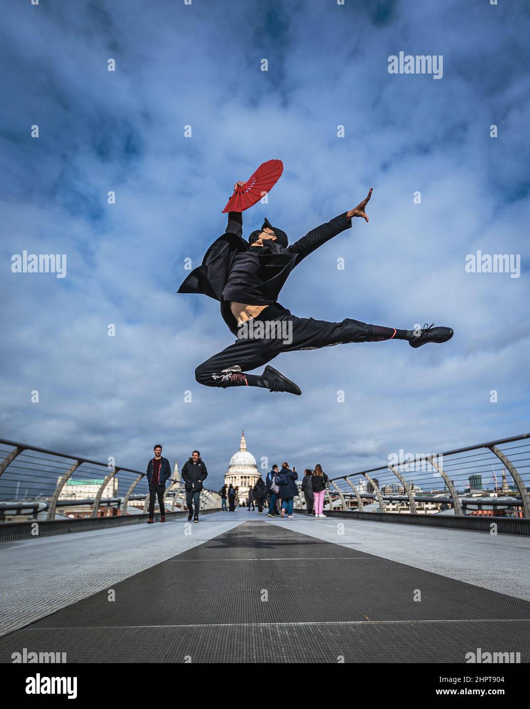 Un artiste martial et une danseuse effectuent des coups de pied élevés sur le Millennium Bridge à Londres. Banque D'Images