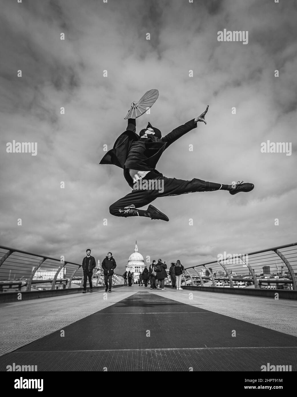 Image en noir et blanc d'un artiste martial, et danseur exécute des coups de pied élevés sur le Millennium Bridge à Londres. Banque D'Images