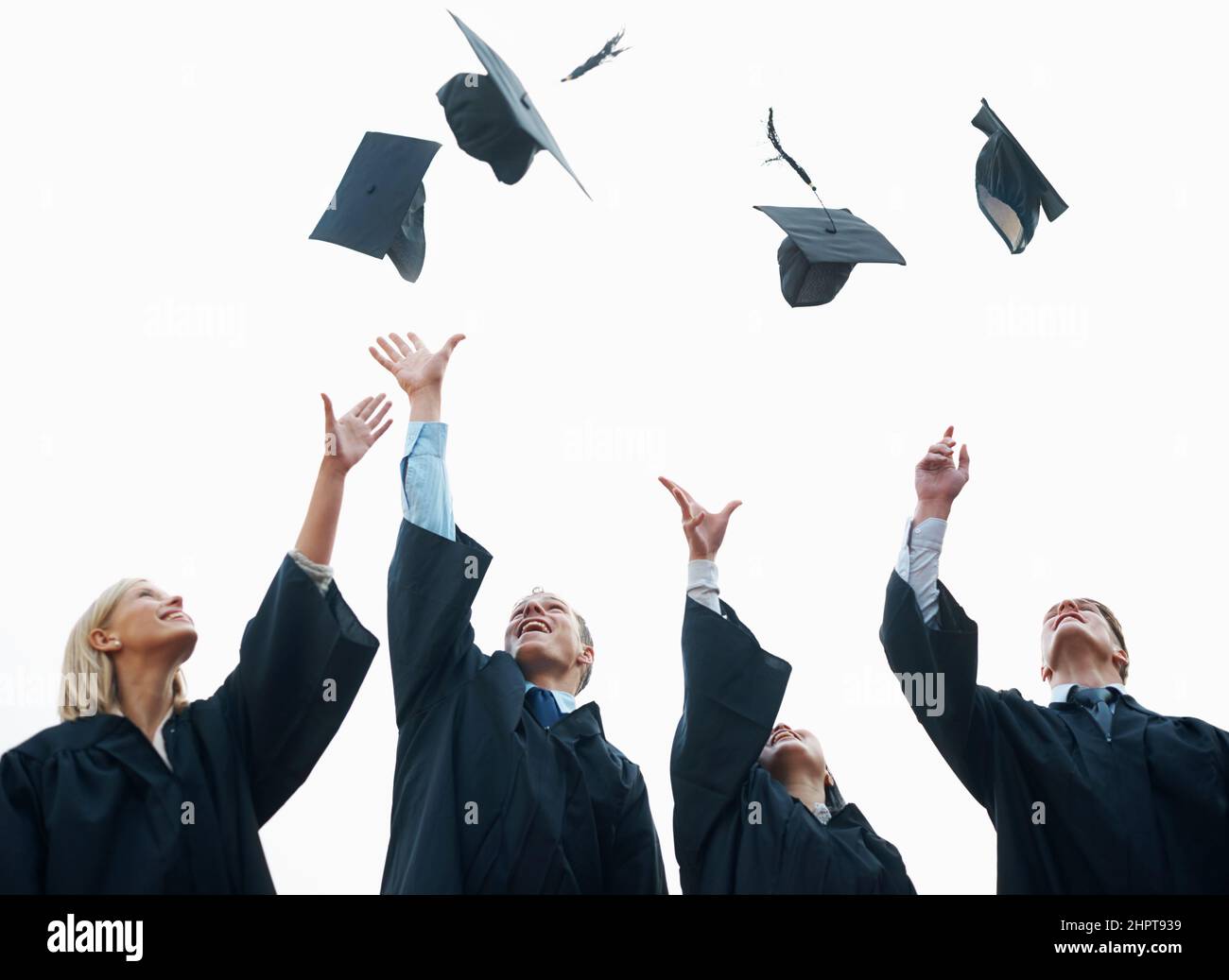 Célébrant le début de leur vie adulte. Un groupe d'étudiants qui jettent leurs casquettes dans l'air après l'obtention de leur diplôme. Banque D'Images