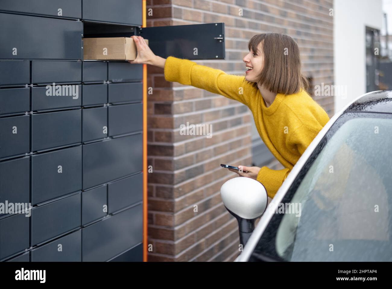 Femme qui reçoit le colis du terminal de poste juste à côté de la fenêtre de la voiture en déplacement Banque D'Images