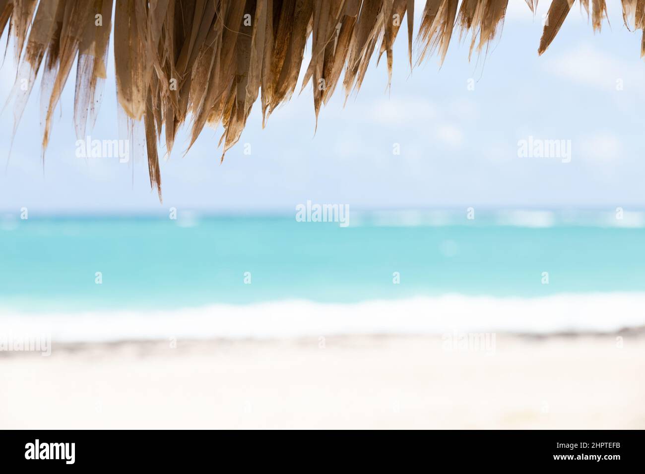 Photo de paysage côtier floue avec plage vide prise sous un parasol en bois. Plage de Bavaro, République Dominicaine Banque D'Images