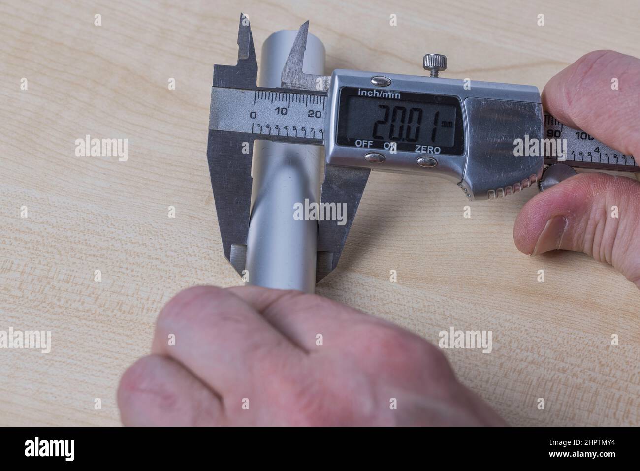 Vue rapprochée des mains homme mesurant un tuyau en aluminium avec des étriers électroniques isolés sur fond blanc. Suède. Banque D'Images