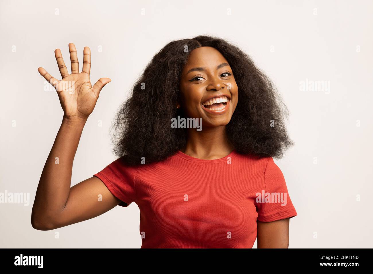 Bonjour. Portrait d'une jeune fille noire joyeuse qui agite la main à la caméra Banque D'Images