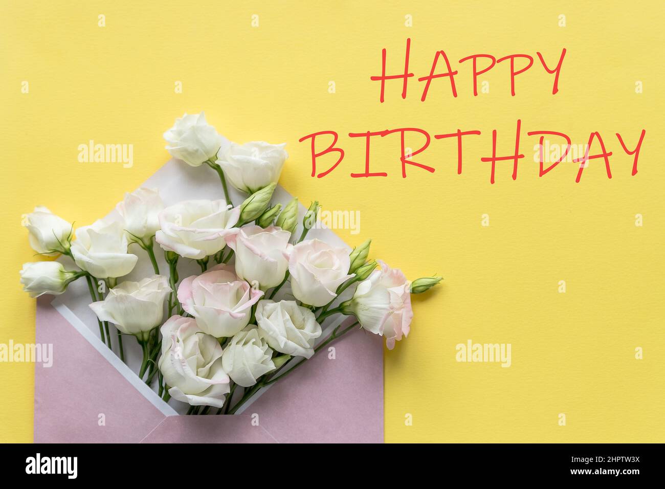 Carte de vœux d'anniversaire élégante. Texte Joyeux anniversaire sur fond jaune.fleurs d'eustoma blanc est dans l'enveloppe. Plat tendance. Banque D'Images