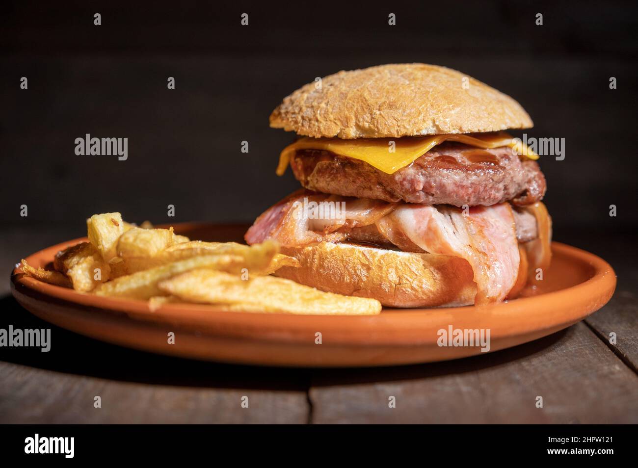 Hamburger de bœuf grillé de qualité supérieure avec bacon, fromage et frites. Délicieux hamburger américain sur fond de bois. Photographie de haute qualité Banque D'Images